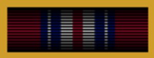 Width-44 Old Glory red ribbon surrounded by gold frame. The ribbon has a central width-3 Old Glory red stripe flanked by pairs of stripes that are respectively width-3 white, width-3 ultramarine blue, width one-half white and width-2 ultramarine blue.