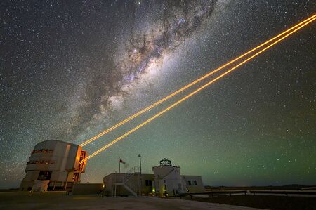 A telescope emitting four orange laser beams.