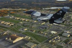 An F-16C Fighting Falcon from the 18th Aggressor Squadron flies over Eielson AFB in 2009. The base's largest hangar, known as the "Thunderdome," is visible in the bottom left of the image.